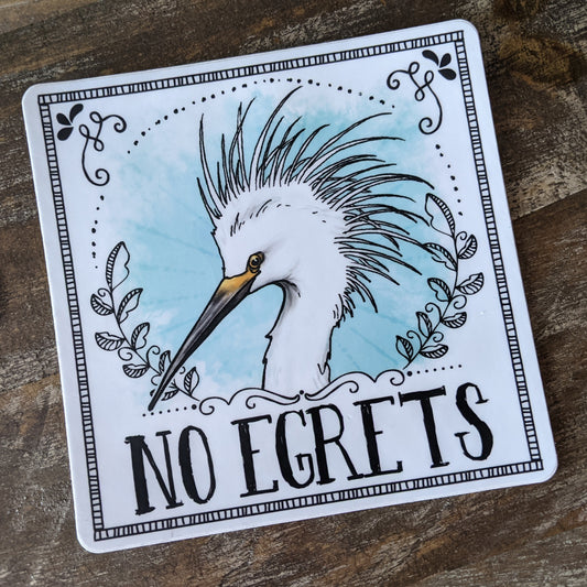 A vinyl decal featuring an illustration of an egret with the text 'NO EGrets' playfully arranged lain on a wooden surface.