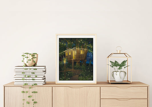 A framed art print of a treehouse featuring a starry sky and fireflies, displayed on a wooden cabinet with plants and decorative items.