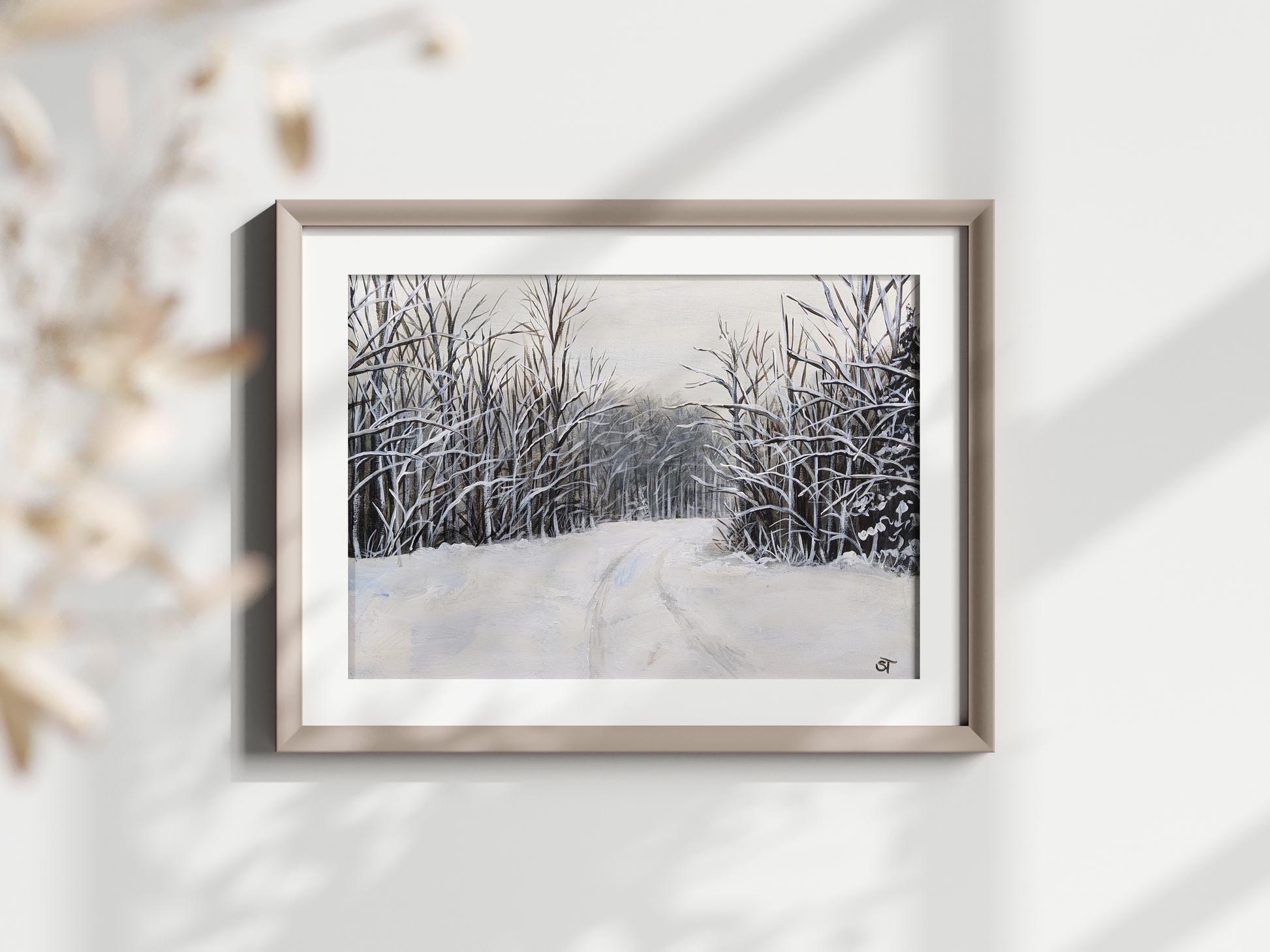 A framed fine art print featuring a winter landscape with snow-covered trees and a rural road, displayed on a white wall.