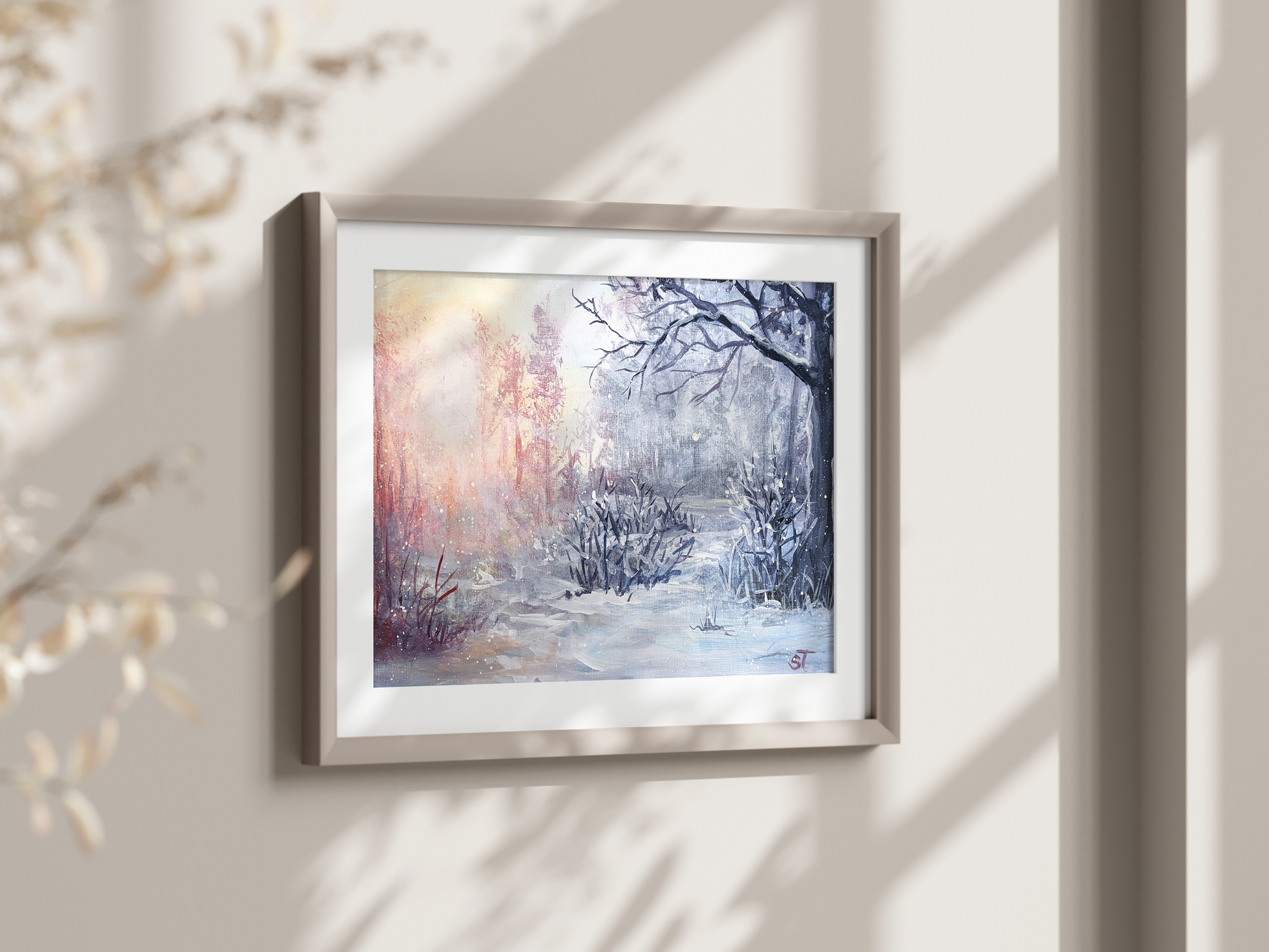 A framed art print featuring a winter forest scene with trees and a warm glow of sunlight, displayed on a wall.