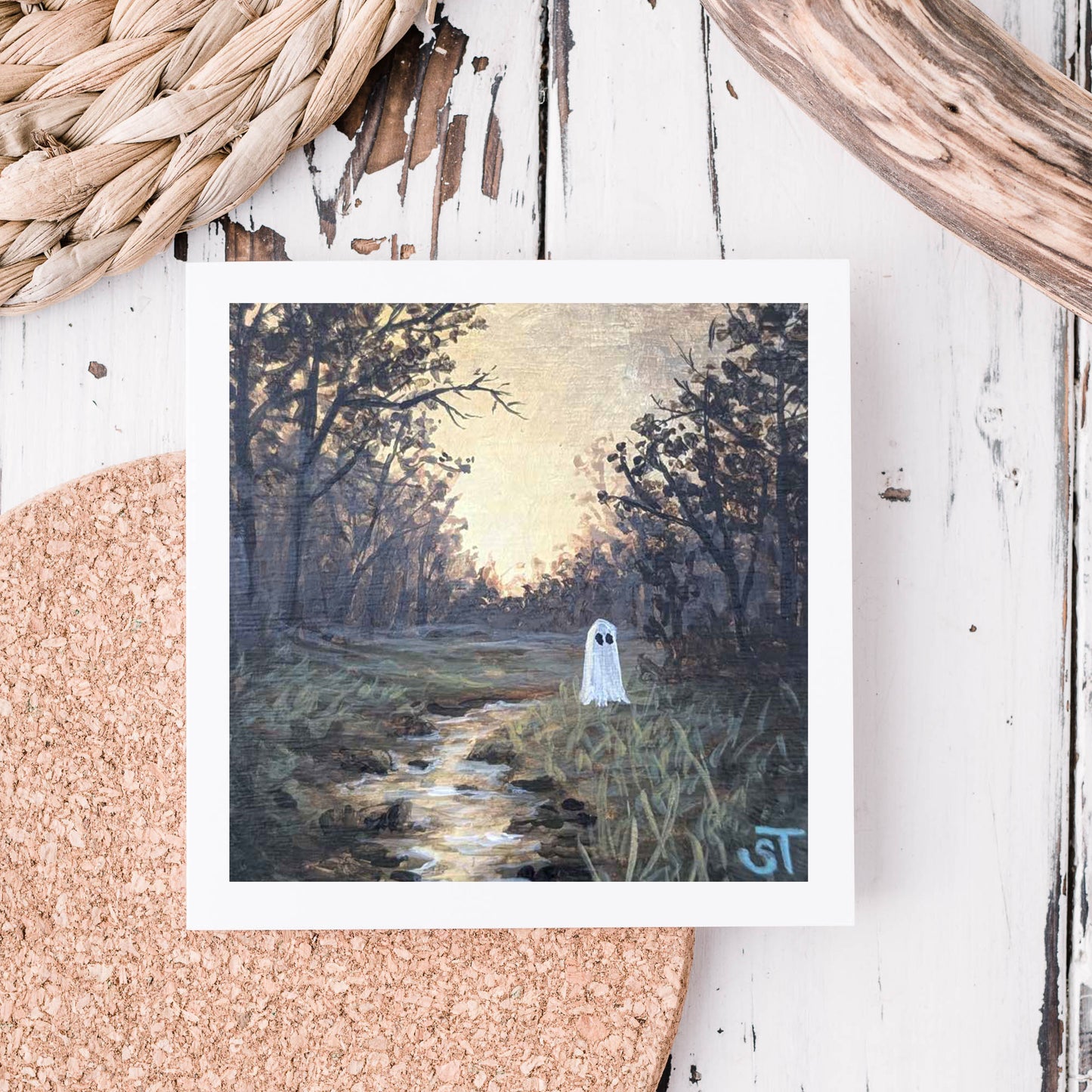 Note card featuring artwork of a ghost by a stream in a forest setting, displayed on a textured background. 
